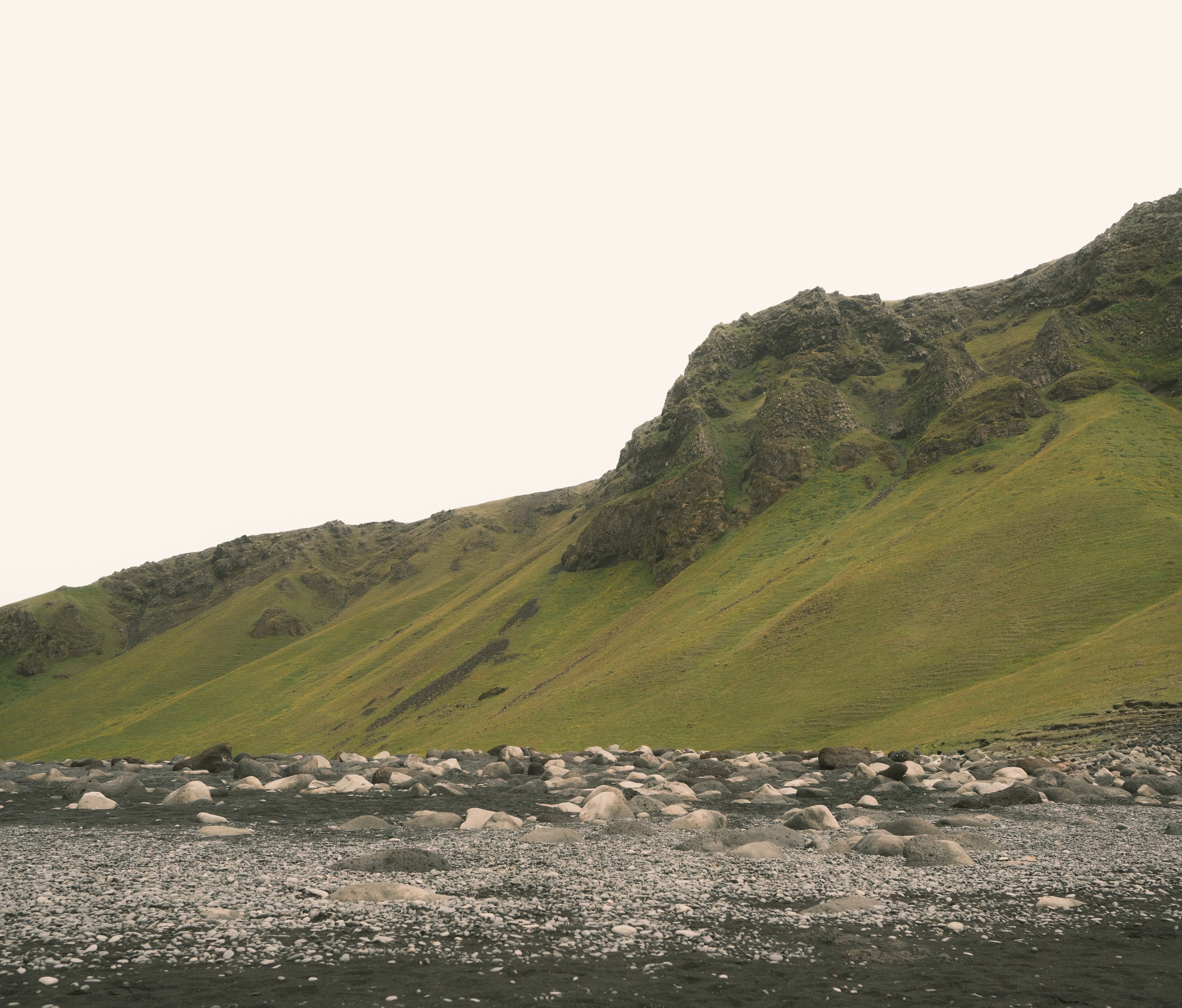 A green mountainside rising from a rocky landscape