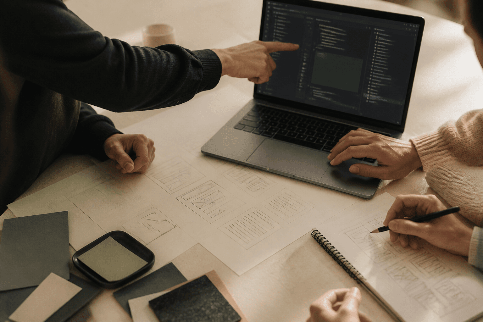 A small team collaborating over interface sketches and code on a laptop
